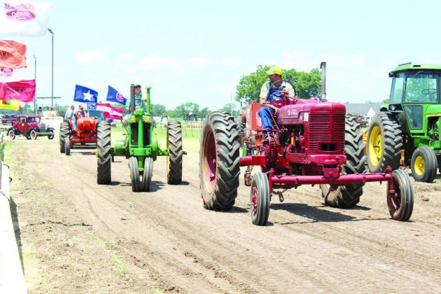 Shelby Smith drives a John Deere tractor and Dylan Smith drives a Farmall tractor during antique tractor parade of the 25th Annual Farming Heritage Festival at Shawnee Feed Center on June 22.