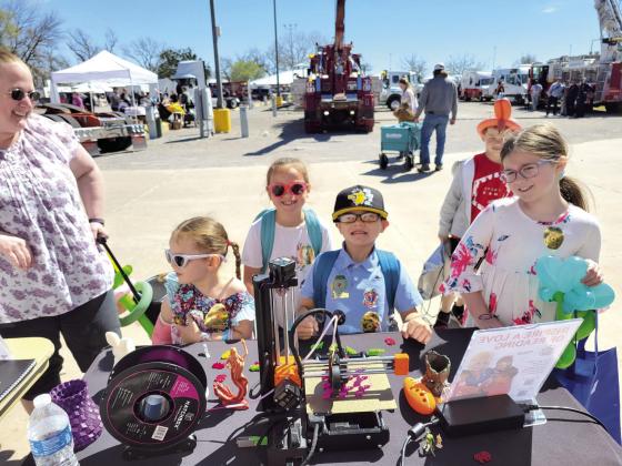 Several children visit the Pioneer Library Systems Maker Mobile where they 3-D printed dinosaurs and personalized bookmarks during the Touch-A-Truck and Beyond event at the CPN Festival Grounds on April 1. Photo provided by Tecumseh Public Library.