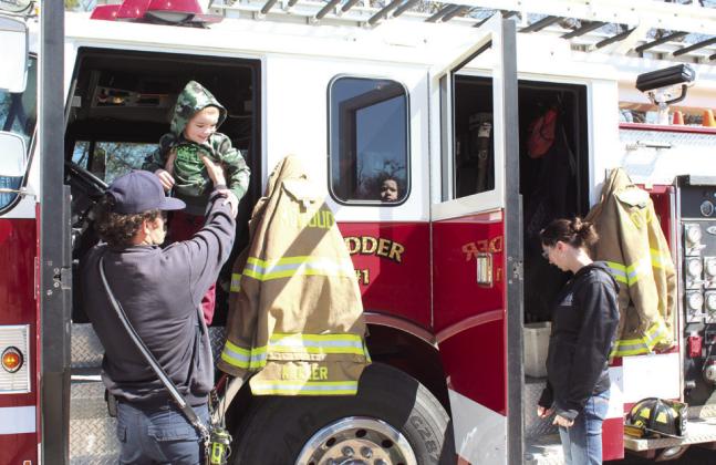 McLoud firefighter Sammy Keller lifts 4-year-old Jackson Bottoms, of Shawnee, down from the fire engine's driver's seat, as Jackson's brother, Jameson Bottoms, 2, looks out the back window during the Touch-A-Truck and Beyond event at the CPN Festival Grounds on April 1. Countywide &amp; Sun/Natasha Dunagan