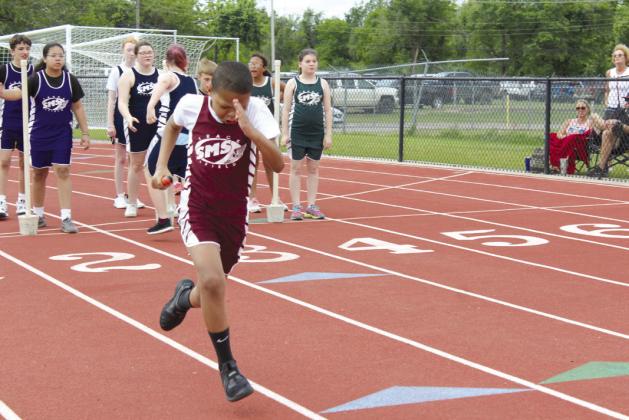 Draedyn Wolf, from Shawnee Middle School, runs the baton, as other sixth-graders from SMS wait for their teammates to make the hand-off.