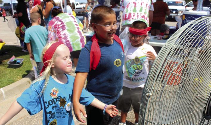 Elinor Peters, 5, Izaiah Peters, 8, and Zaden Peters, 7, all of Shawnee, cool off in front of a misting fan beside the Vision Bank tie-dye tent at Cops N' Kids on Aug. 23. An estimated 2,000 people attended the event at the Heart of Oklahoma Expo Center, said Founder and Coordinator Shawnee Police Cpl. Vivian Lozano-Stafford in an email. It offered more than 30 emergency response agencies and about 25 organization booths.