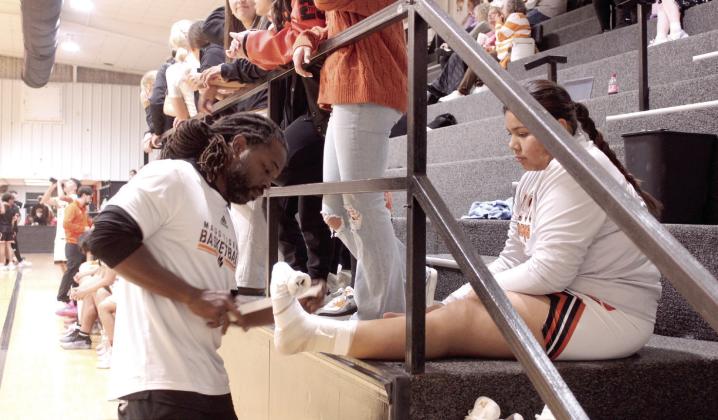 Maud Boys Basketball Assistant Coach Royce Street wraps Natalie Brown's foot and ankle during the Maud 8-Man Basketball Tournament on Dec. 4.
