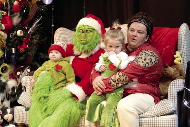 The Grinch poses with Cade Glasgow, six months; Karsin Glasgow, 2; and Ashley Glasgow, all of Tecumseh, during the Grinchmas Whoville event, held in the Tecumseh City Hall Auditorium on Nov. 30, 2023. File photo.