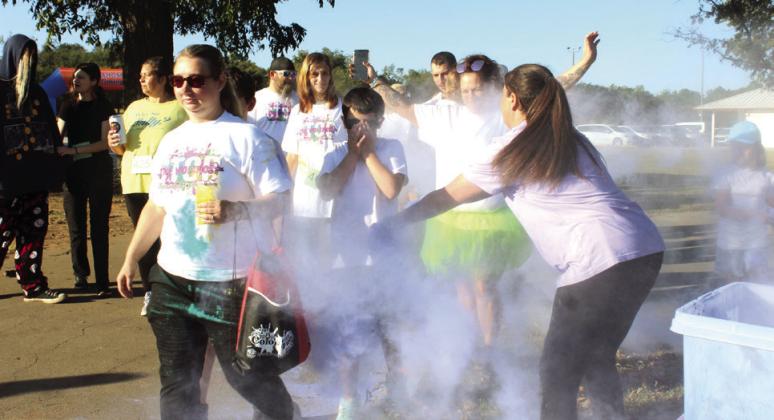 House of Hope Shelter Manager Danielle Hasler and Raelin Wallace, far right, pour purple powder onto participants. Natasha Dunagan, Countywide &amp; Sun