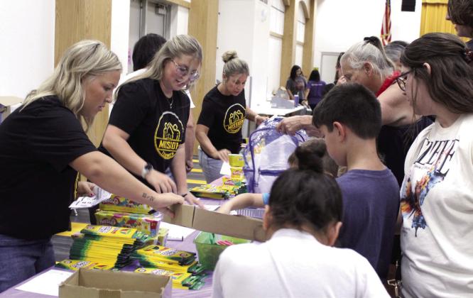 Twins Elise Whitney and Ella (Whitney) Gardner and their mother, Hope Whitney, volunteer at the Mission Tecumseh Back to School Bash, held at the Tecumseh High School W.P. Wood Alumni Center on July 25. Photos by Natasha Dunagan, Countywide &amp; Sun