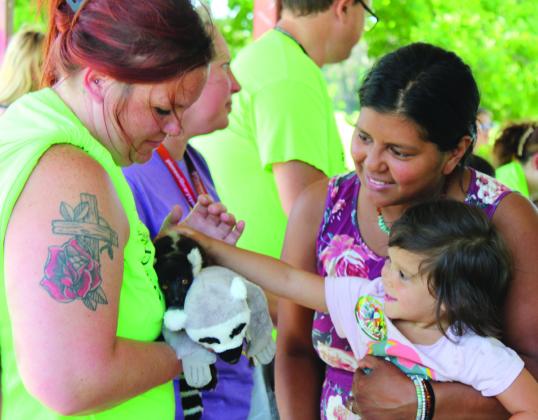 Rhema Brynildsen, 3, is held by her mother, Katrina Brynildsen, both of Tecumseh, as she pets Mort the baby Black-and-White Ruffed Lemur during the Tecumseh Pioneer Library Summer Reading Challenge Extreme Animals program on June 13. This is one of 60 species of lemur found in Madagascar, said handler Keeley Knowles, who also spoke on Burmese pythons, bearded dragons, blue-tongued skinks, European hedgehogs and armadillos. Holding Mort is CPN/CDC After-School Program teacher Kristen Janway.