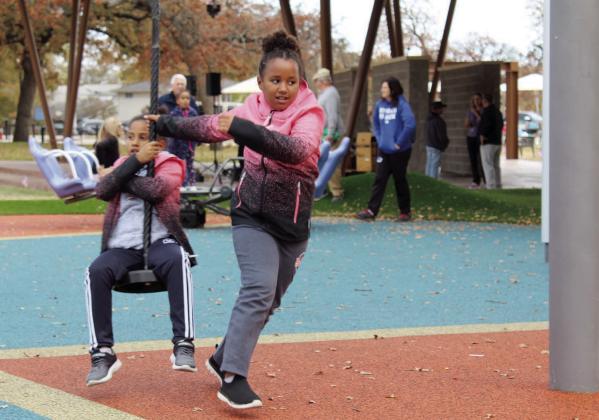 Twins Alexia and Nadine Nsabimana, age 8, of Shawnee, have fun on the rope swing merry-go-round during the Woodland Veterans Park Grand Re-Opening on Nov. 11. Countywide &amp; Sun/Natasha Dunagan
