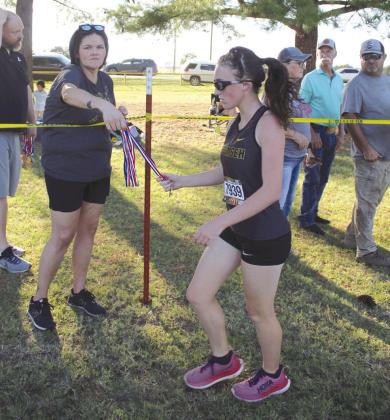 Tecumseh junior Harper Stone gets a medal from retired coach and counselor Melissa Poole after placing fourth in the High School Girls Two-Mile division.