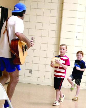 Brothers Jack Lewis, 6, and Frankie Lewis, 4, both of Macomb, march behind Syman Hajjar, of Hot Toast Music Company, in the "Dinosaur Parade" on July 30, during the "Musical Moods" program at the Tecumseh Public Library.
