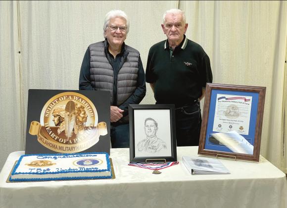 Dr. James Myers, of Tulsa, and Skip Myers, of Tecumseh, pose by a portrait of their father, Tech Sergeant Verdun C. Myers, following a ceremony in which the late WWII veteran was inducted into the Oklahoma Military Hall of Fame. The ceremony was held at American Legion Post 16, in Shawnee, on Dec. 21. Photo provided by OKMHF Ambassador John Farris.