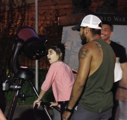 Serena Braden, 7, of Tecumseh, looks in awe of Jupiter and its moons, as her father, Kevin Braden, waits his turn.