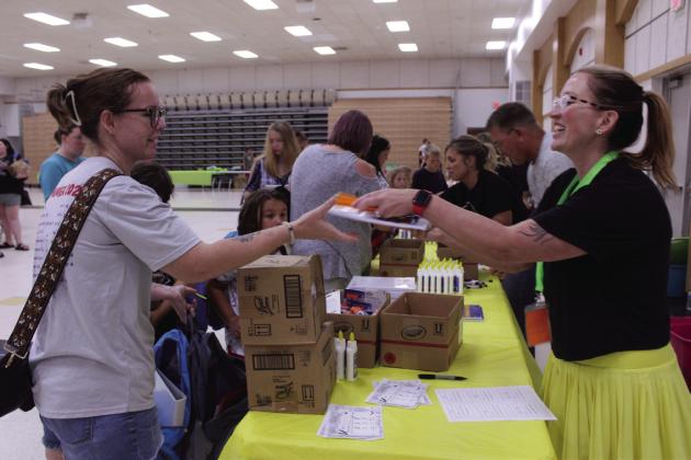 Megan Roller, right, gives out paper and pencils during Mission Tecumseh's 11th Annual Back to School Bash at the W.P. Wood Alumni Center on July 26. M.T.