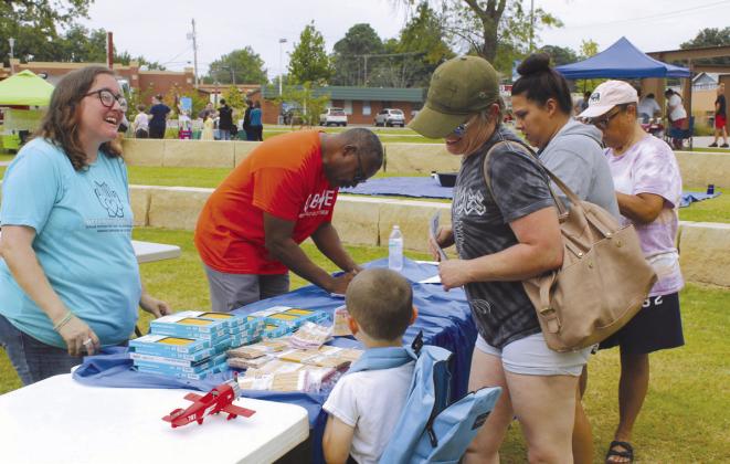 Emily Streeter, founder of the Pottawatomie County Giving Project (PCGP), talks with Katrina Raines and Cannon Winsett, 5, both of Shawnee, as Dunbar Heights Community Group (DHCG) President Timmy Young checks off another family's list.