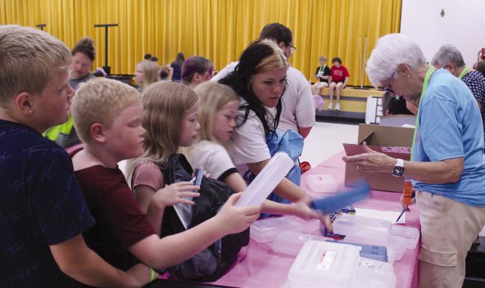 A family visits the pencil box booth, as volunteer Susan Tischer, right, goes over their supply list during Mission Tecumseh's 11th Annual Back to School Bash.