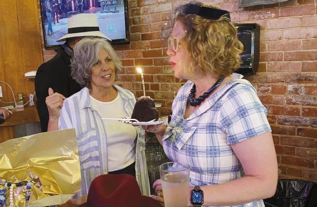 Celebrity Model Greta Shuler blows out a candle to celebrate her birthday during the fashion show. Also shown is Sharon Gerards, who dressed Shuler for the event. The fashion outfit included a hat and necklace belonging to Gerard's grandmother. Later, Gerards and Shuler graciously offered up the entire outfit, including a purse from Shuler's collection, to the impromptu auction.
