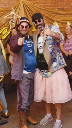 Celebrity Model Chris Odneal poses with his designer, Dave Anderson. Odneal was fashioned to wear an oversized track suit, undersized Thunder jersey and butterfly glasses... topped off with a Trump bucket hat. Odneal accessorized his fit with a Bernie Sanders 'cape' and cowboy boots.