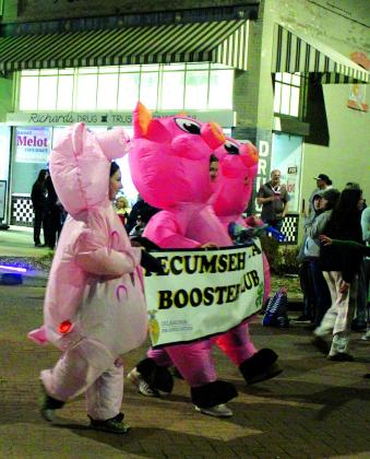 Three agriculture students in inflatable pig costumes carry the Tecumseh 4-H &amp; FFA Booster Club banner in the Shawnee Christmas Parade. Countywide &amp; Sun/Natasha Dunagan