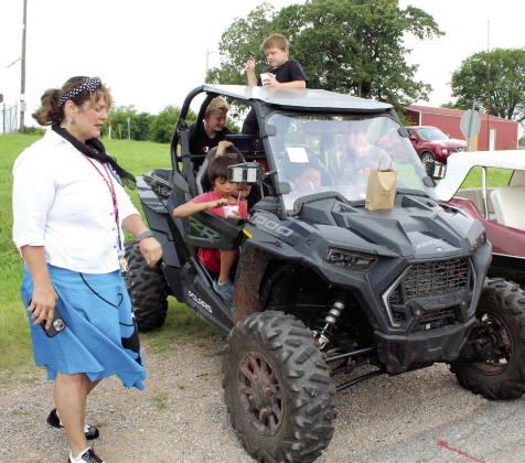 Several boys enjoy sitting in a 2023 Polaris Razor, which belongs to the grandfather of one of them, Howell Girod of Macomb. Shannon Browning, far left, the Macomb Summer School Program Director, was informing them of lunchtime on June 23. With a “Time Travel Summer” theme for the program, the Macomb Car Show was held for the first time in conjunction with 1950s week.