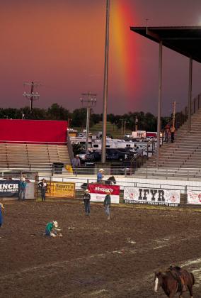 Mackenzie Floyed, of Ville Platte, LA, ties a goat as a rainbow over the Heart of Oklahoma Expo Center signals the end of rain on the opening night of the International Finals Youth Rodeo, July 7. Countywide &amp; Sun/Natasha Dunagan