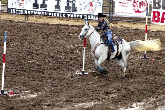 Kinzlee Jones, of Shawnee, weaves through the pole bending event in deep mud during the International Finals Youth Rodeo on July 7. Countywide &amp; Sun/Natasha Dunagan