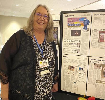 Suzie Campbell poses next to the display of first place winners with her series on domestic violence.