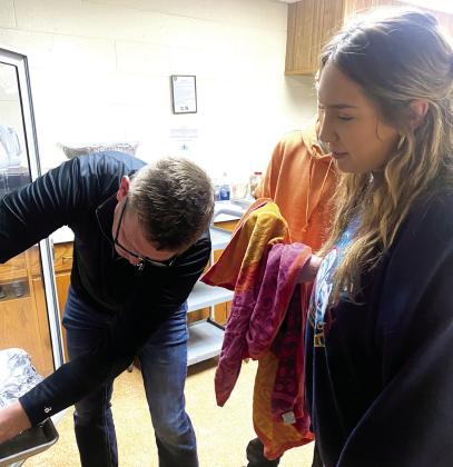 Jerry Kuhn carefully places a tray of dressing in the warmer while Jaxon and Jacey watch. Photo provided