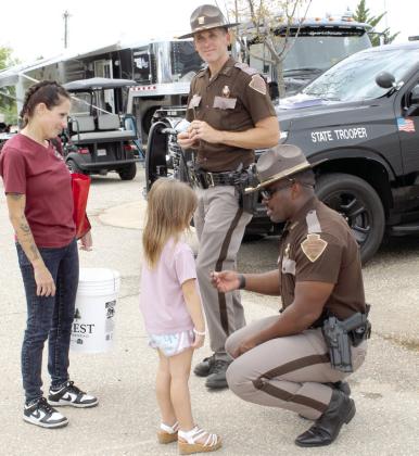 Trooper RJ Walker, kneeling, and Trooper Chad Pape, standing, with the OK Highway Patrol, hand out stickers.