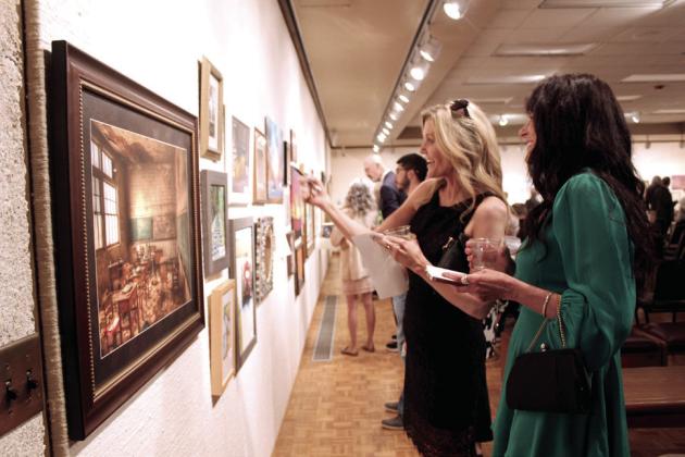 April Armer of Edmond and Julianne Clark of Shawnee take notes on works of art donated for the event. The piece in the foreground is a photograph of a schoolroom in Skedee, OK by Vernon Hatley. Natasha Dunagan, Countywide &amp; Sun
