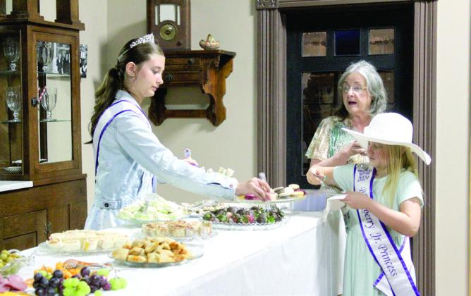 As Glenda Kuhn, center, speaks, Blackberry Princess Haylee Kimsey, left, and Blackberry Junior Princess Riley Sherman demonstrate the right way to fill their plates using tongs. Natasha Dunagan, Countywide &amp; Sun
