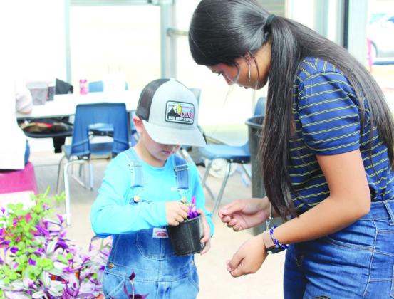 McLoud FFA Reporter Mayrin Perez advises as Gauge Colwell, 7, plants cuttings in a pot at the McLoud FFA Plant Sale on Oct. 19. Colwell is the brother of McLoud FFA Chaplain Gunner Colwell. This was the first plant sale for the chapter since they got their new climate-controlled greenhouse. Countywide &amp; Sun/Natasha Dunagan