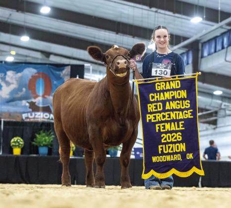 Taycie Baker of Bethel poses with her heifer, Chili, and a banner after winning the "Grand Champion Red Angus Percentage Female" at The Fuzion by NAJRAE in Woodward last month. Photo provided