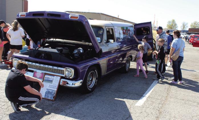 At the Bethel Band Boosters Car Show, a family admires the artwork and reads about 'Plum Crazy,' a 1966 Chevy Panel Truck belonging to Michael Frederick of Shawnee. Frederick said his 17-year-old son, Eugene, did 90 percent of the restoration on the panel truck, beginning when he was 13. The artwork was done by Cameron Dyer of Passion Works Body Shop. Natasha Dunagan, Countywide &amp; Sun
