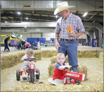 Lane Nagy, 2, and Oaklee Franks, 3, both of Tecumseh, drive tricycles around the Children’s Barnyard, as their grampa Dee Baldridge watches over them, at the Pottawatomie County Free Fair on Sept. 9. Countywide &amp; Sun/Natasha Dunagan