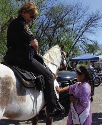 Angelica Star Pepiakitah, the 2023 McLoud Blackberry Festival Junior Princess, pets Princess the paint horse, ridden by McLoud Police Department Detective Jan Montgomery, during the Touch A Truck and Beyond event, April 6, at the CPN Festival Grounds. Countywide &amp; Sun/Natasha Dunagan