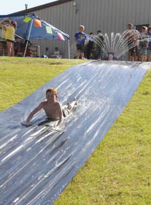 Gunner Billins, 10, of Bethel, cools off on the slip n’ slide, a fund-raiser for the Bethel Little League Cheer program, on Aug. 17. This was one of several booths, including a dunk tank fund-raiser for Bethel Wrestling, at the Bethel High School Blue &amp;amp; Gold Bash held at the football field. Countywide &amp;amp; Sun/Natasha Dunagan