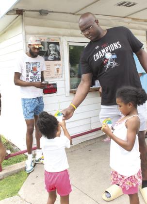Potawatomi Fire player Paul Harrison hands snow cones to his daughters Alana Harrison, 4, and Skylar Harrison, 6, during Epic Snocones' Juneteenth celebration on June 19. Also shown is Jachai Simmons. Business owner David Henry invited the Potawatomi Fire team and also had a bounce-house for the kids. Natasha Dunagan, Countywide &amp; Sun