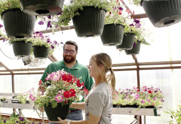 Tecumseh FFA member Addison Taron assists Corey Wilson with a hanging basket of petunias. In addition to hanging baskets, they offered bedding and vegetable plants with more varieties of tomatoes, peppers and petunias than in past years. Natasha Dunagan, Countywide &amp; Sun