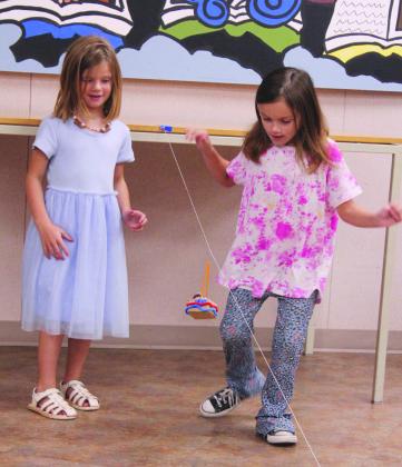 Charlotte Muir and Sarah Sprague, both 6 and from Tecumseh, test their zip line container, which holds a ping pong ball, during the 'Build It: Zip Line Zoom' program at the Shawnee Public Library on July 21.