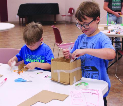 Tut Clagg, 5, and Glen Clagg, 8, both of Shawnee, work on separate zip line containers during the 'Build It: Zip Line Zoom' program at the Shawnee Public Library on July 21. The event was led by 4-H Educator Kacie Jasper, along with State 4-H STEM Innovators Tori Nelms, Tony Nelms and Madison Maddox.