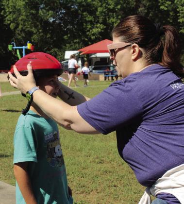 Pottawatomie Go (POGO) volunteer and elementary school nurse Amanda Hunt fits Carson Hall, 7, of Shawnee, for a helmet during POGO's Pedalpalooza. Hunt said they had about 144 helmets to give away during the event. Natasha Dunagan, Countywide &amp; Sun