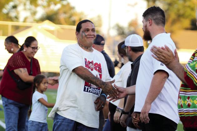 Native American Artist Nicholas Blanchard shakes hands with Shawnee Public Schools Director of Finance Tristan Wyatt and other SPS employees during the recognition of the tribes at Jim Thorpe Night. Blanchard painted a mural in honor of Sac &amp; Fox member Jim Thorpe at Jim Thorpe Stadium, and an unveiling and ribbon-cutting was held earlier that evening.