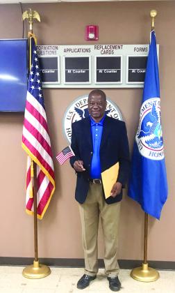 Rev. David Henry, of Shawnee, poses with the U.S. and Homeland Security flags at his naturalization ceremony on April 30. Photo provided.