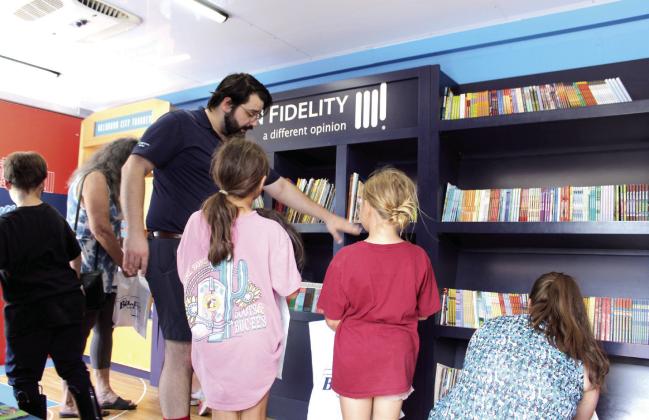 Seth Parker, Thunder Community Outreach Coordinator, shows two girls where they can find books for their age range on the Rolling Thunder Book Bus. Parker said they offer free books to those in kindergarten through fifth grade, and they travel around the state to libraries, schools and museums. A Tecumseh Fire Department fire engine was also there, as well as The Snow Shak with free snow cones.