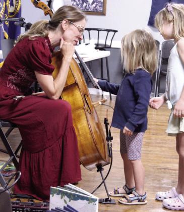 Elanor Roberts, 6, of McLoud, strums the strings on Erin Yeaman's cello.