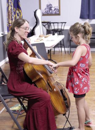 Alivia Bivings, 6, of Dale, tries playing Erin Yeaman's cello with a bow. For more information on upcoming programs, visit https://pioneerlibrarysystem.org/.