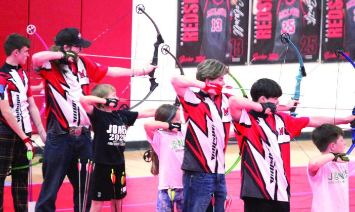 In the red, white and black shirts, from left, Langston Ellison, Dakota Fox, Gunner Moss and Ryan Walls shoot for McLoud High School during the 2026 Oklahoma Centershot Bullseye State Tournament, held at MHS on April 10. Also shown are three archers from Jones. Natasha Dunagan, Countywide &amp;amp; Sun