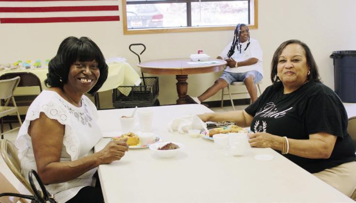 Barbara Jefferson and Denise Elix enjoy a fish-fry lunch at the Brooksville Community Center, as Diannia Ervin-Wilson, in background, waits to take donations. Jefferson and Elix were born and raised in Brooksville and now reside in Shawnee.