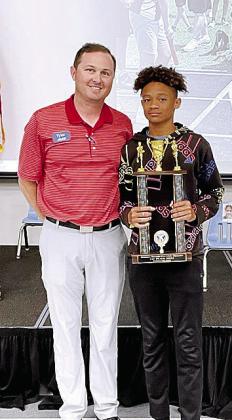 Tyler Wilburn, of Arvest, presents the Division I Shawnee Middle School - Purple trophy to sixthgrader DeWayne Wallace. He won three events at Little Olympics at the Tecumseh High School Track. Photo provided.