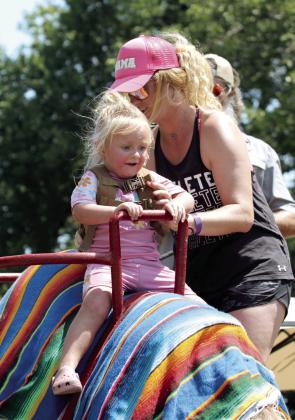 Mackenzie Climer of Tecumseh sits her daughter, Ember Climer, 2, on a camel before joining her during the FireLake Fireflight Balloon Festival on Aug. 9. Two camels from Camels Unlimited in Adair gave rides in the Kids' Zone.