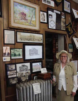 Tecumseh Historical Society member Arthenia Haney, dressed as Kate Barnard, rings a school bell amidst the display about Barnard and the elementary school named after her on April 11. Haney will be playing Barnard again for the Tecumseh Museum's 30th Anniversary Open House on April 19 from 10 am to 2 pm. Prints of the Tecumseh Centennial painting by Barbara Hertz will also be in a silent auction that day. Natasha Dunagan, Countywide &amp; Sun